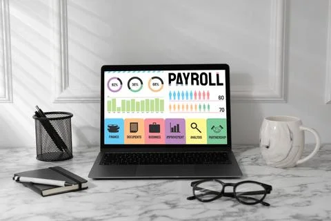 Laptop with payroll data on screen on table Stock Photos