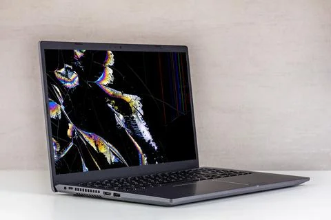 Laptop pc with a broken screen in cracks and with leaking crystals on a gray  Stock Photos