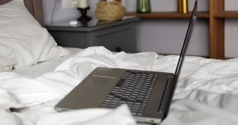 Laptop placed on bed in modern apartment room highlights concept of freelance Stock Footage 307870464