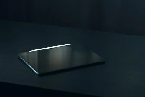 Laptop placed on a dark surface in a dimly lit room during the evening hours Stock Photos