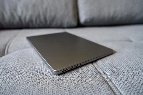 Laptop placed on a gray couch surface Stock Photos
