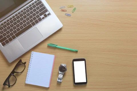 Laptop placed near a empty notebook and blank smartphone on a brown wooden fl Stock-Fotos