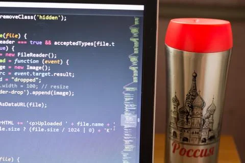 Laptop with programming web code and red capped flask aside Foto stock