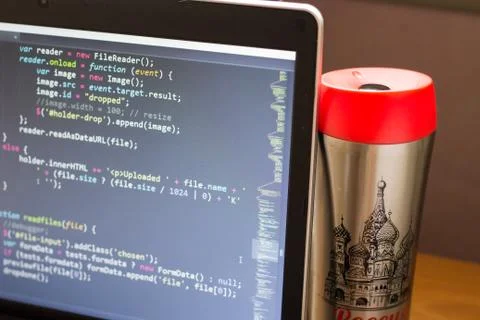Laptop with programming web code and red capped flask aside Foto stock