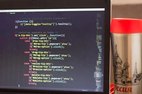 Laptop with programming web code and red capped flask aside Foto stock