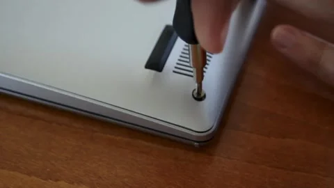 Laptop repair. A man's hand is using a screwdriver to unscrew bolts from a Stock Footage 297071157
