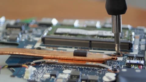 Laptop repair. Using a hand screwdriver, the person unscrews the screws holding Stock Footage 304879649