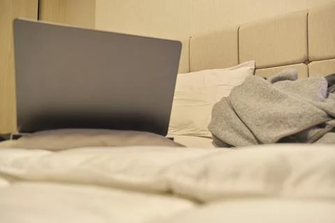 Laptop resting on bed representing remote work comfort Fotos de archivo