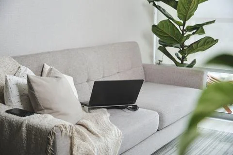 Laptop resting on stand on comfortable sofa in cozy living room for working from Stock Photos