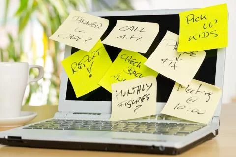 Laptop screen covered with sticky notes with different appointments on brown  Stock Photos