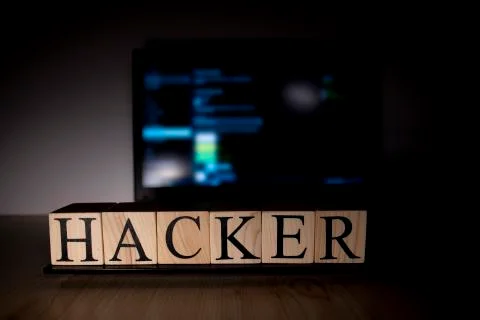 The laptop screen on the table is open. Hacker word on wooden cubes on laptop Foto stock