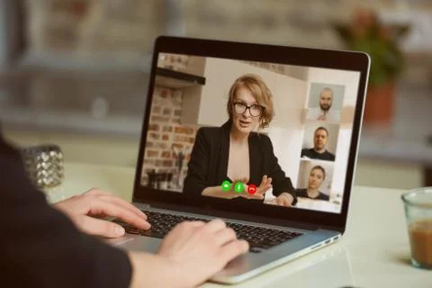 Laptop screen view over a woman's shoulder. A girl works remotely on a comput Stock Photos