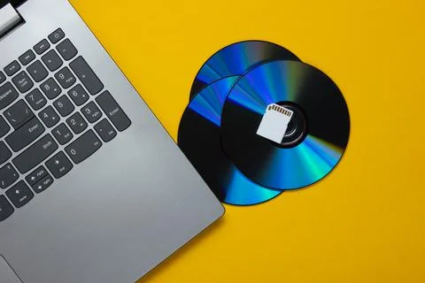 Laptop, SD memory card, cd drives on yellow paper background. Modern and obso 写真素材