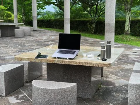 Laptop sits open on stone table outdoors Stock Photos