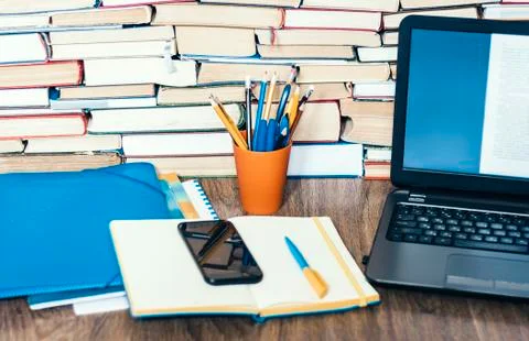Laptop, smartphone, stack of books, notebook and pencils in orange plastic ho Stock Photos