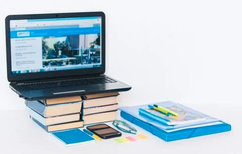 Laptop, smartphone, stack of books, notebook and pens on white wooden table,  Stock Photos