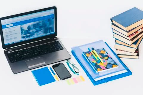 Laptop, smartphone, stack of books, notebook and pens on white wooden table,  Stock Photos
