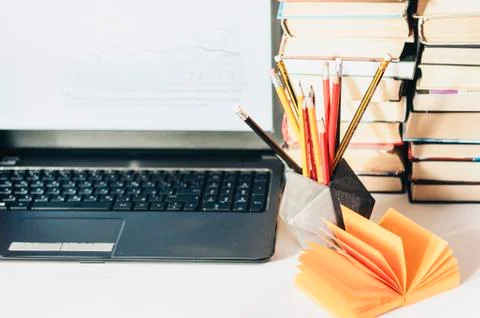 Laptop, stack of books, notebook, pencils in office background for education  Stock Photos