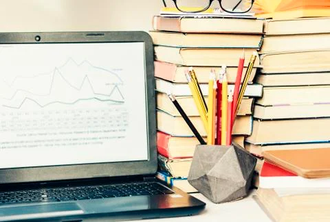 Laptop, stack of books, notebook, pencils in office background for education  Stock Photos