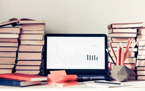 Laptop, stack of books, notebooks and pencils on white table, education offic Stock Photos