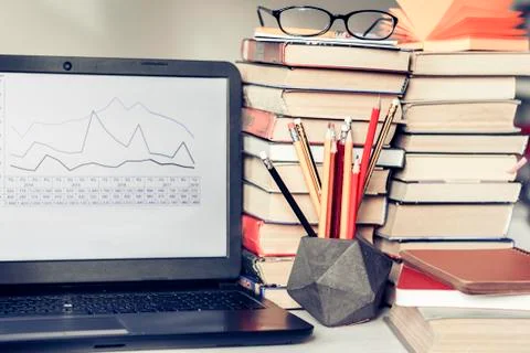 Laptop, stack of books, notebooks and pencils on white table, education offic Stock Photos
