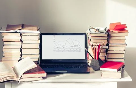Laptop, stack of books, notebooks and pencils on white table, education offic Stock Photos