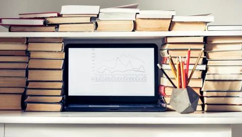 Laptop, stack of books, notebooks and pencils on white table, education offic Stock Photos