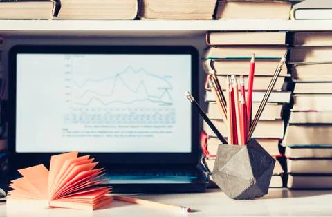 Laptop, stack of books, notebooks and pencils on white table, education offic Stock Photos