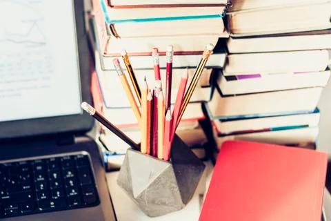 Laptop, stack of books, notebooks and pencils on white table, education offic Stock Photos