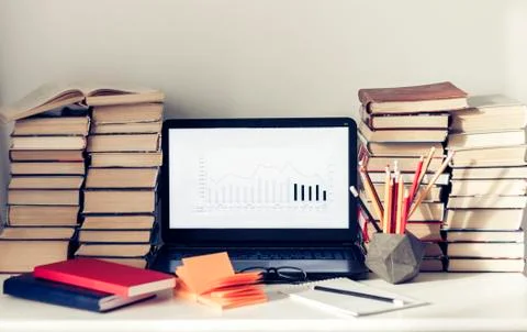Laptop, stack of books, notebooks and pencils on white table, education offic Stock Photos