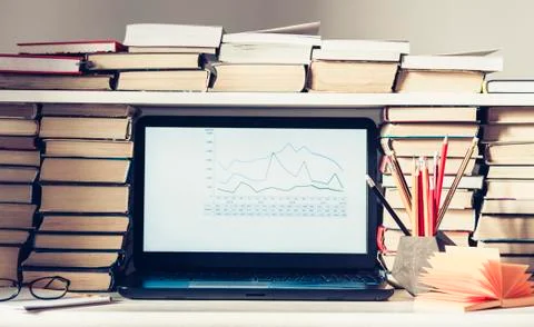 Laptop, stack of books, notebooks and pencils on white table, education offic Stock Photos