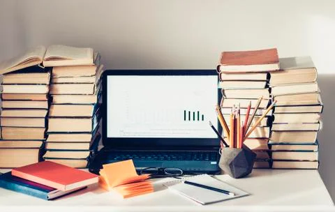 Laptop, stack of books, notebooks and pencils on white table, education offic Stock Photos
