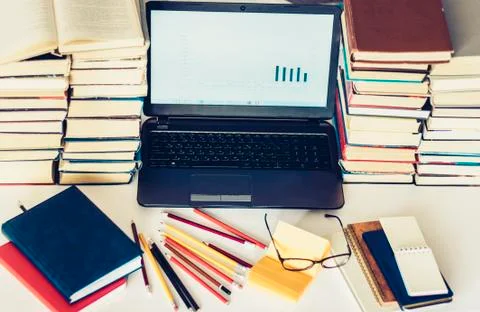 Laptop, stack of books, notebooks and pencils on white table, education offic Stock Photos
