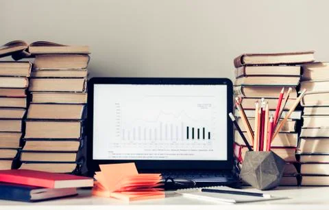 Laptop, stack of books, notebooks and pencils on white table, education offic Stock Photos