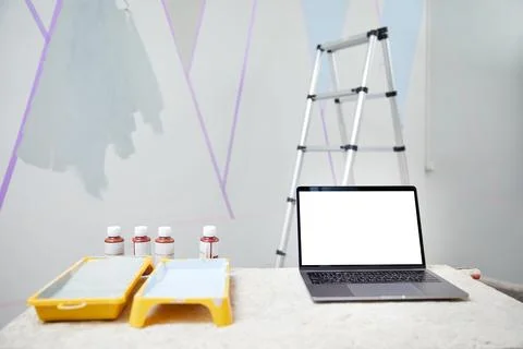 Laptop standing on table with white copy space mockup with wall being painted on Stock Photos