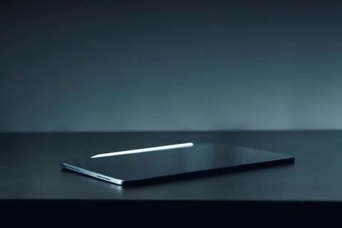 Laptop on a table in a dimly lit room during evening hours Stock Photos