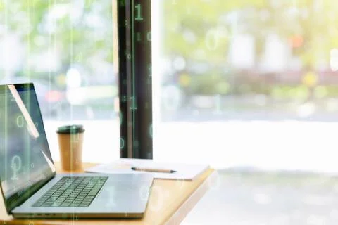 A laptop on a table near a large table without people, a glass with a drink. Stock Photos
