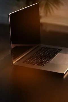 Laptop on a table with a soft light in a workspace during evening hours Stock Photos