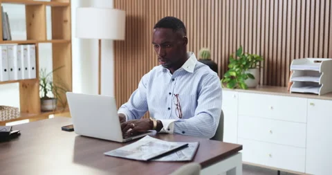 Laptop, typing and black man in office with research, documents and report for Stock Footage 330061179