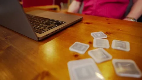 Laptop user sits at desktop with flash memory data cards on workspace Stock Footage 319819055
