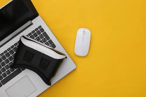Laptop with VR glasses on yellow background. The virtual reality. Modern gadg 库存照片