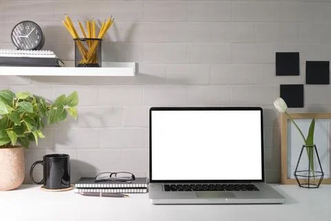 Laptop white empty screen, picture frame, potted plant and supplies on whit.. Stock Photos