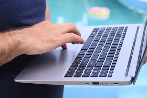 Laptop worker using laptop beside swimming pool, Fotos de archivo