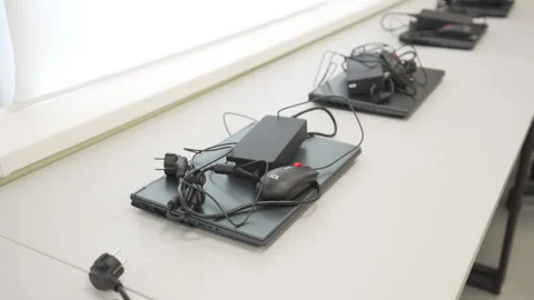 Laptops with coiled power cords and wired mice on desk Stock Footage 310245900
