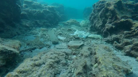 Large accumulation of plastic debris at bottom in crevice between stones, Slow Stock Footage 255112440