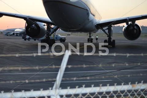 Large airliner with barbed wire fence in foreground. Stock Photos
