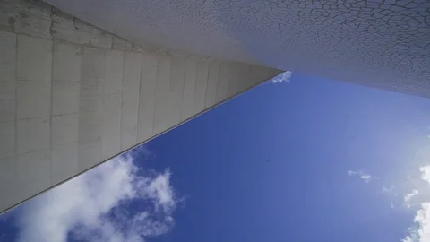 A large airplane flies low over the modern building Tenerife auditorio. The Stock Footage 116133722
