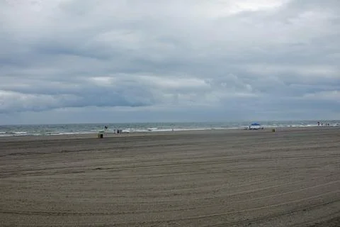 Large almost empty beach with storm clouds over the ocean Stock Photos