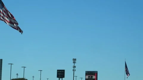 A large American flag flying on a pole next to a billboard advertisement fo.. Stock Footage 333478839