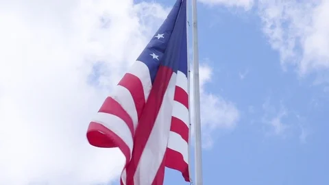 Large American Flag Flying Under Bright Blue Cloudy Sky 動画素材 79861818